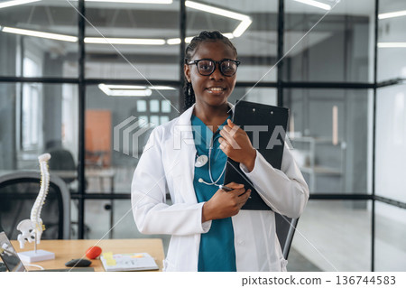 In white coat. Female doctor in coat is in the office clinic In white coat. Female doctor in coat is in the office clinic 136744583
