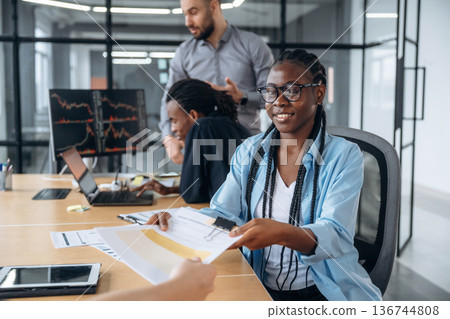 Giving the documents. Business people are working in the office Giving the documents. Business people are working in the office 136744808