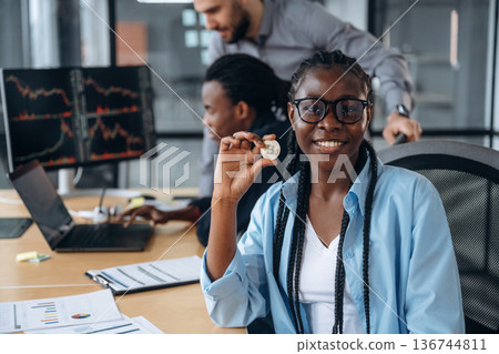 Crypto coin in hand of woman. Business people are working in the office Crypto coin in hand of woman. Business people are working in the office 136744811
