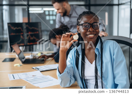 Crypto coin in hand of woman. Business people are working in the office Crypto coin in hand of woman. Business people are working in the office 136744813