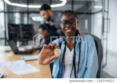 Crypto coin in hand of woman. Business people are working in the office Crypto coin in hand of woman. Business people are working in the office 136744815