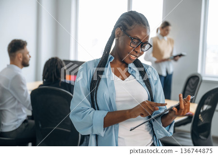 Woman is standing and smiling. Business people are working in the office Woman is standing and smiling. Business people are working in the office 136744875