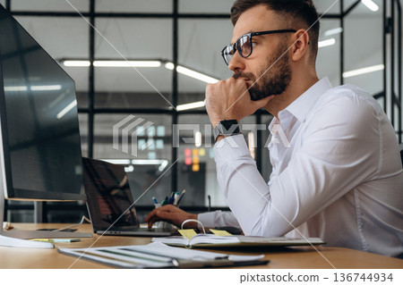 Business person is sitting by computer in office and working 136744934