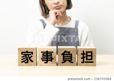 一位身穿圍裙的女子手持一塊寫著「家務負擔」的積木。 136745068