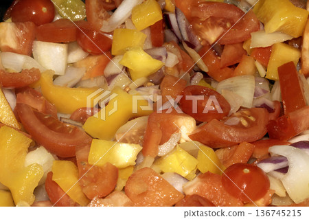 Close up of mixed fried vegetables chopped tomatoes, onions and peppers frying 136745215