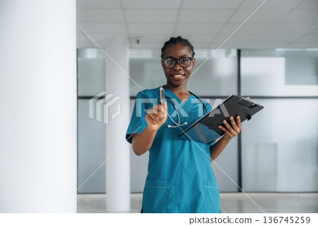 In glasses, standing. Female doctor is indoors in modern room 136745259