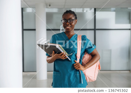 Medical student. Woman with pink backpack is indoors Medical student. Woman with pink backpack is indoors 136745302