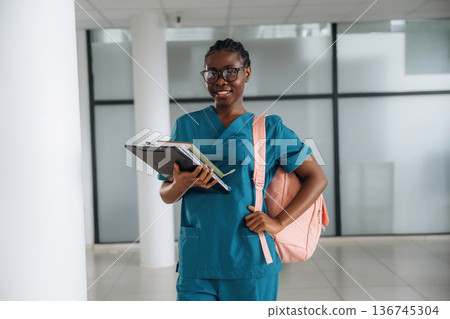Medical student. Woman with pink backpack is indoors Medical student. Woman with pink backpack is indoors 136745304