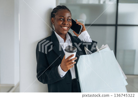 Talking by phone. Businesswoman in formal clothes is in the modern room Talking by phone. Businesswoman in formal clothes is in the modern room 136745322