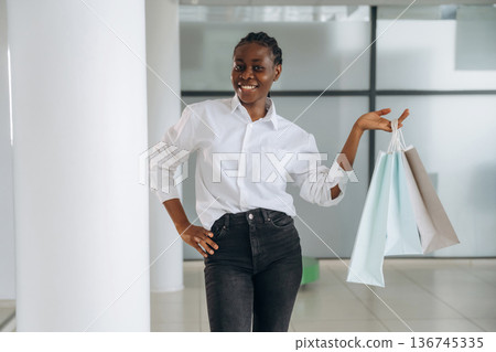 Shopping bags in hands. Businesswoman in formal clothes is in the modern room Shopping bags in hands. Businesswoman in formal clothes is in the modern room 136745335