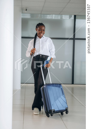 Suitcase is on the floor, ready for vacation. Businesswoman in formal clothes is in the modern room Suitcase is on the floor, ready for vacation. Businesswoman in formal clothes is in the modern room 136745387