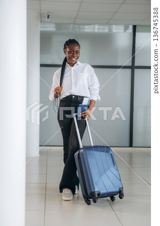 Suitcase is on the floor, ready for vacation. Businesswoman in formal clothes is in the modern room 136745388