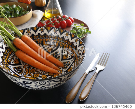 Vegetables in colorful ceramic plates. Healthy eating. Patterned bowl on black background. Modern porcelain tableware. Food and traditional cuisine. Top view. Vegetables in colorful ceramic plates. Healthy eating. Patterned bowl on black background. Modern porcelain tableware. Food and traditional cuisine. Top view. 136745460
