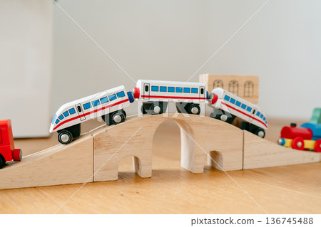 Wooden toy train crossing small bridge on track. Eco-friendly educational toy in minimalist interior. Concept of sustainable children products and creative play 136745488