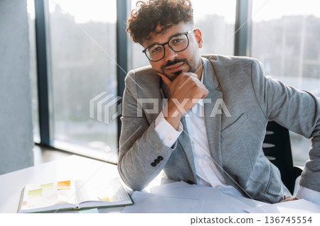 Sitting by the table. Businessman is in the office 136745554