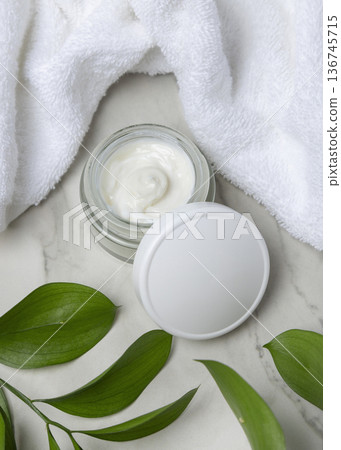 Cosmetic mockup, opened face cream jar with blank lid near white bath towel and green leaves Cosmetic mockup, opened face cream jar with blank lid near white bath towel and green leaves 136745715