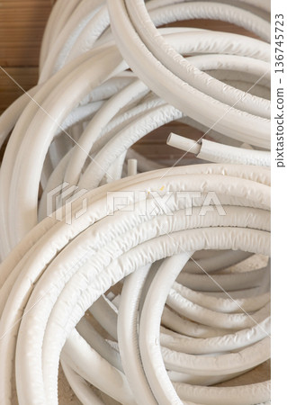 Coiled white insulated pipes. Flexible tubing materials for residential building construction Coiled white insulated pipes. Flexible tubing materials for residential building construction 136745723