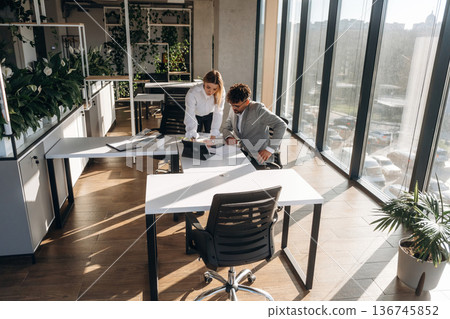 Illuminated by sunlight. Man and woman are indoors in modern building 136745852