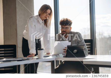 Digital tablet and documents. Man and woman are indoors in modern building Digital tablet and documents. Man and woman are indoors in modern building 136745859