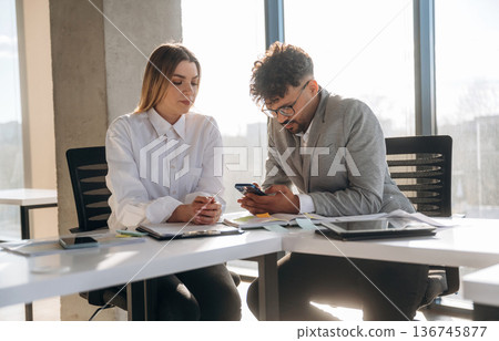 Cooperation, working on project. Man and woman are indoors in modern building Cooperation, working on project. Man and woman are indoors in modern building 136745877