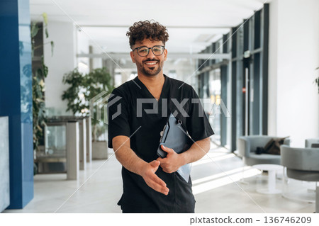 Nice to see you, giving hand to shake. Male doctor is indoors in the modern building Nice to see you, giving hand to shake. Male doctor is indoors in the modern building 136746209