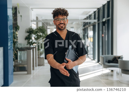 Nice to see you, giving hand to shake. Male doctor is indoors in the modern building Nice to see you, giving hand to shake. Male doctor is indoors in the modern building 136746210