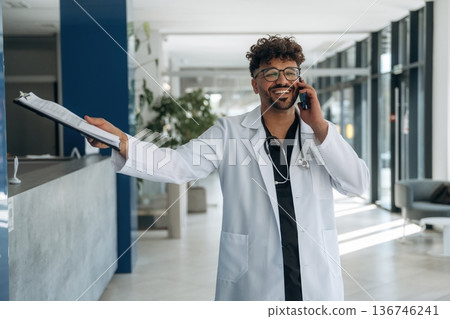 Conversation by phone. Doctor is indoors in the modern building Conversation by phone. Doctor is indoors in the modern building 136746241