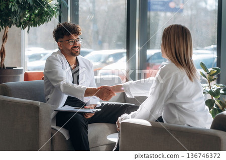 Sitting and talking. Man and woman are indoors in modern building 136746372