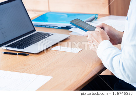 A man preparing his tax return using a computer and smartphone 136746553