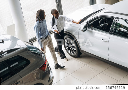With notepad, helping. Car seller is assisting client in the automobile salon With notepad, helping. Car seller is assisting client in the automobile salon 136746619