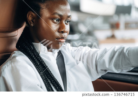 Serious facial expression. Woman in white shirt is in the modern car Serious facial expression. Woman in white shirt is in the modern car 136746715