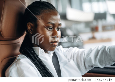 Serious facial expression. Woman in white shirt is in the modern car 136746716