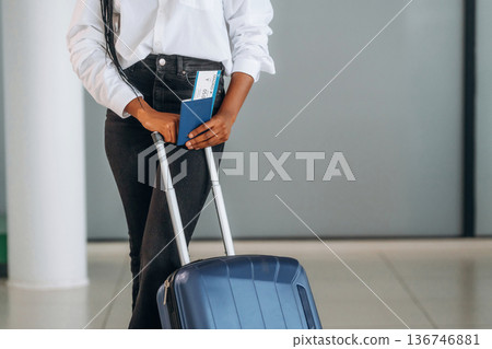 Woman is standing with suitcase, documents and airplane tickets 136746881