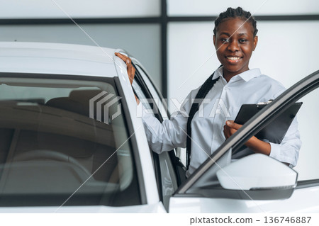 Friendly, smiling. Car seller, businesswoman is standing in automobile salon Friendly, smiling. Car seller, businesswoman is standing in automobile salon 136746887