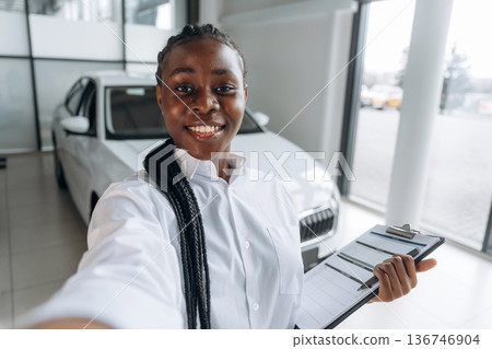 Making the selfie, smiling. Car seller, businesswoman is standing in automobile salon 136746904