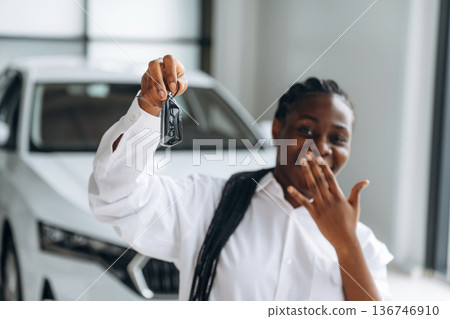 Buy new vehicle now, with keys in hands. Car seller, businesswoman is standing in automobile salon Buy new vehicle now, with keys in hands. Car seller, businesswoman is standing in automobile salon 136746910