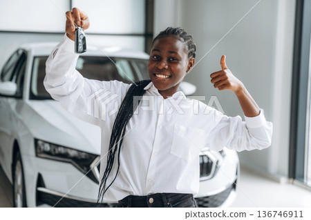 Buy new vehicle now, with keys in hands. Car seller, businesswoman is standing in automobile salon Buy new vehicle now, with keys in hands. Car seller, businesswoman is standing in automobile salon 136746911
