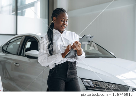 Car seller, businesswoman is standing in automobile salon Car seller, businesswoman is standing in automobile salon 136746913