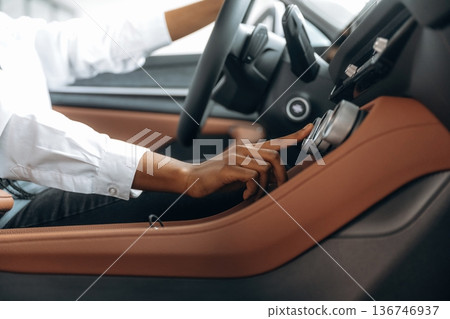 Pressing the button. Woman in white shirt is in the modern car Pressing the button. Woman in white shirt is in the modern car 136746937