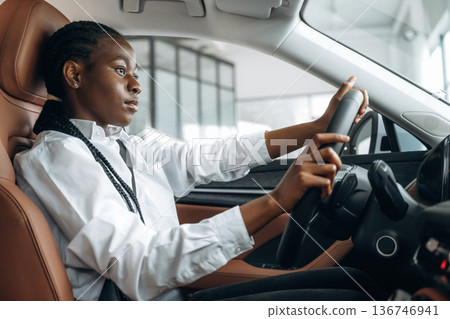 Serious facial expression. Woman in white shirt is in the modern car 136746941