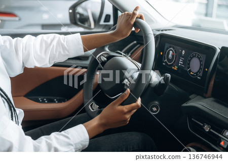 Control concept, hands on steering wheel. Woman in white shirt is in the modern car 136746944