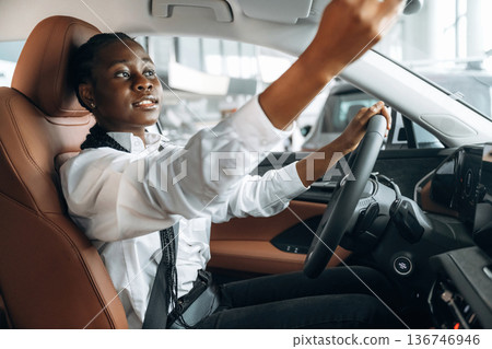 Looking in the mirror. Woman in white shirt is in the modern car Looking in the mirror. Woman in white shirt is in the modern car 136746946