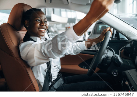 Looking in the mirror. Woman in white shirt is in the modern car Looking in the mirror. Woman in white shirt is in the modern car 136746947
