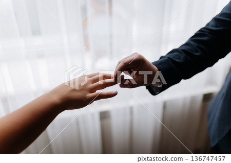 Groom placing wedding ring on brides finger during intimate marriage ceremony moment Groom placing wedding ring on brides finger during intimate marriage ceremony moment 136747457
