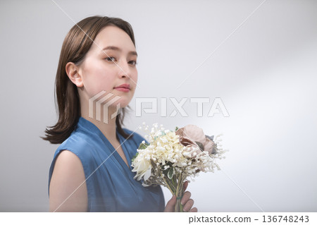 Woman in a blue blouse holding a bouquet Woman in a blue blouse holding a bouquet 136748243