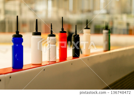View of many different water bottles standing on the side of the ice arena View of many different water bottles standing on the side of the ice arena 136748472