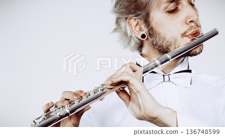 Male flutist playing his flute closeup Male flutist playing his flute closeup 136748599