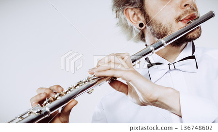 Male flutist playing his flute Male flutist playing his flute 136748602