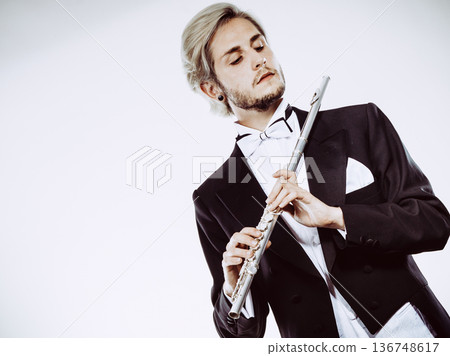 Male flutist wearing tailcoat holds flute Male flutist wearing tailcoat holds flute 136748617