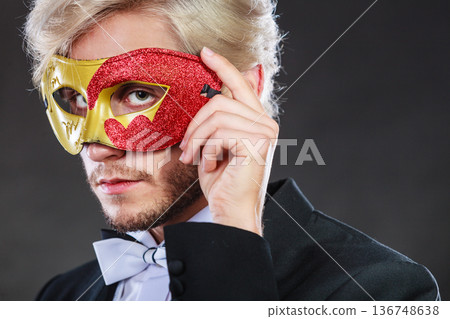Young man in carnival mask on dark Young man in carnival mask on dark 136748638